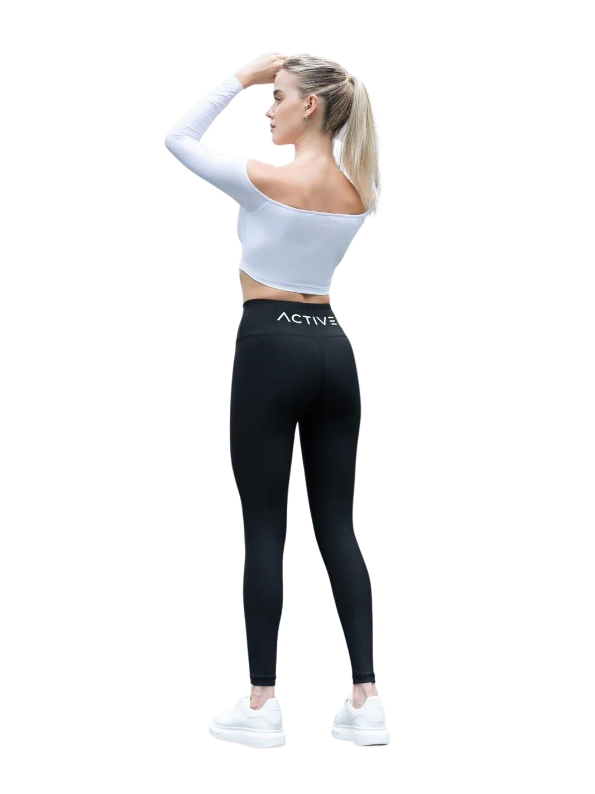 Frau im schulterfreien Langarm-T-Shirt Comfortlux von Lismina, in einer Yoga-Pose in schwarzen Leggings und weißen Turnschuhen.